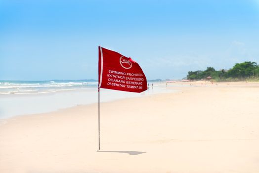 Season of storms. Red flag on the sand beach with no Swimming sign .