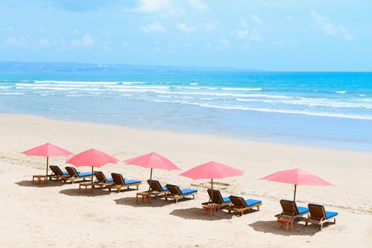View of nice tropical empty sandy beach with umbrellas and beach beds