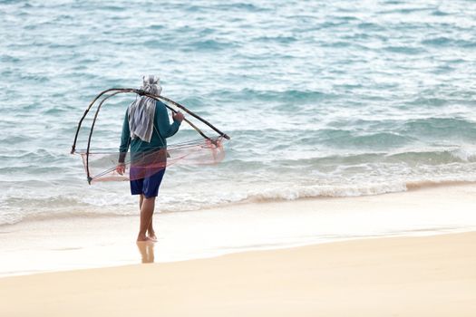 Man with net walk on the sea sand coast, Thailand