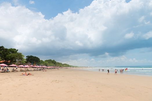 SEMINYAK, BALI - SEP 27: Wide sand beach with tourists, umbrellas and beds on Sep 27, 2012 in Seminyak, Bali, Indonesia. The five km long sandy stretch of Kuta is arguably the best beach front in Bali.  