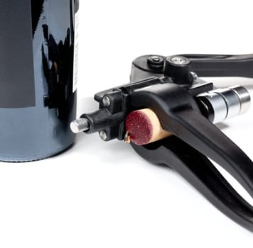 Cork from red wine bottle in front of bottle in modern cork screw remover
