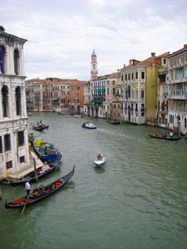 A scene of gondolas gliding through the canals of Venice, Italy. There is also Italian architecture and buildings visible.