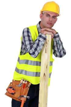 A carpenter leaning one a piece of wood.