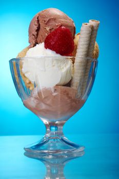 ice cream in with strawberries and chocolate. closeup .on blue background.