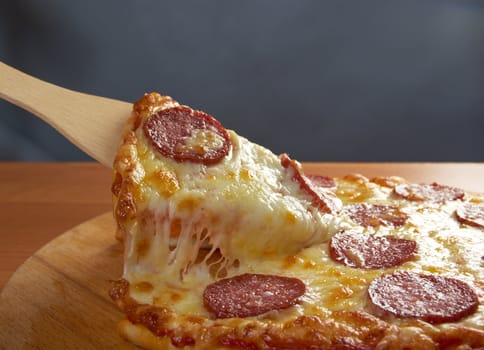 homemade pizza  Pepperoni .taking slice of pizza,melted cheese dripping.