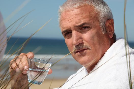 Man sat alone on beach in dressing gown