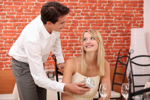 Man giving surprise gift to woman in restaurant