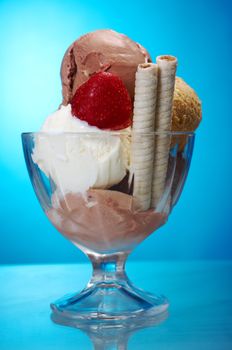 ice cream in with strawberries and chocolate. closeup .on blue background.