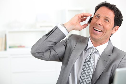 mature man wearing grey suit with tie is laughing