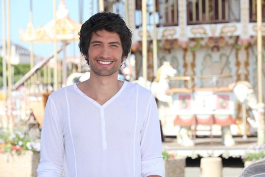 man posing in front of a carousel