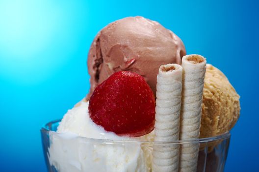 ice cream in with strawberries and chocolate. closeup .on blue background.