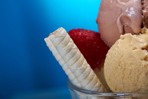 ice cream in with strawberries and chocolate. closeup .on blue background.