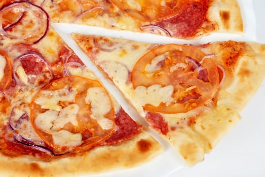pizza closeup with salami, tomato, onion and mozzarella cheese