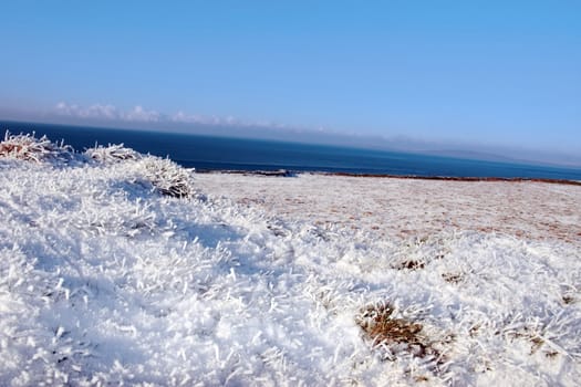 a seasonal snow frosty covered grass ditch with a view of the atlantic ocean