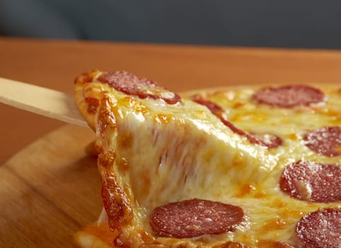 homemade pizza  Pepperoni .taking slice of pizza,melted cheese dripping.
