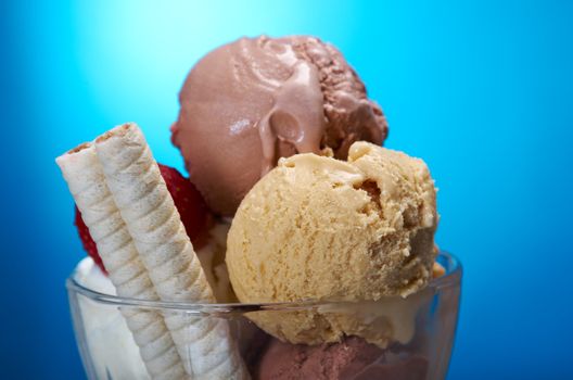 ice cream in with strawberries and chocolate. closeup .on blue background.