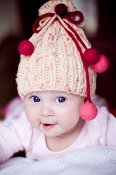 cute surprised baby girl in yellow hat with colourful bobbles
