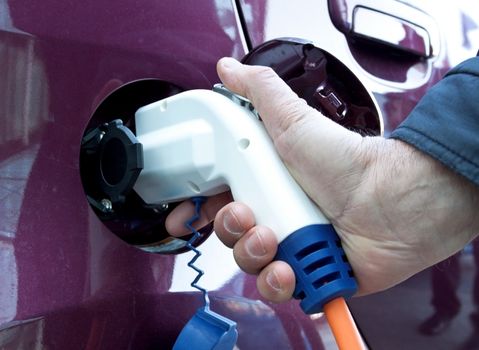 Close-up of male hand pluging in electric car
