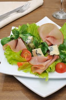 Appetizer with ham and blue cheese in lettuce leaves with corn salad

