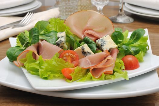 Appetizer with ham and blue cheese in lettuce leaves with corn salad