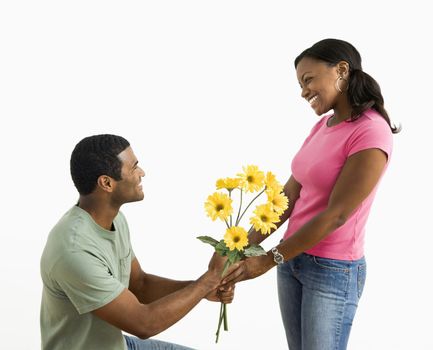 African American male giving pretty female a bouquet of yellow flowers.