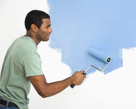 African American man painting wall blue.