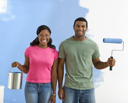 African American couple next to half-painted wall with paint supplies-American Gothic-style.