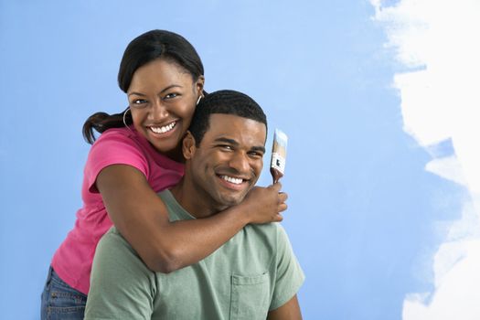 Portrait of African American male and female couple next to half-painted wall.