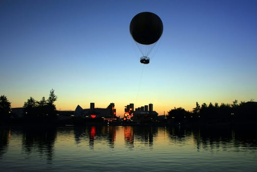 The silhouettes of buildings and a balloon at sunset.