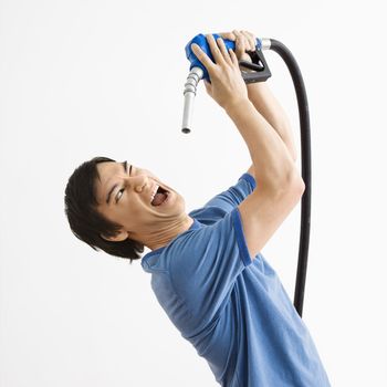 Asian young man fighting with gasoline pump nozzle.