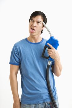 Asian young man holding gasoline pump nozzle to his forehead with disgust on his face.