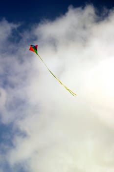 Colorful kite in flight against white clouds