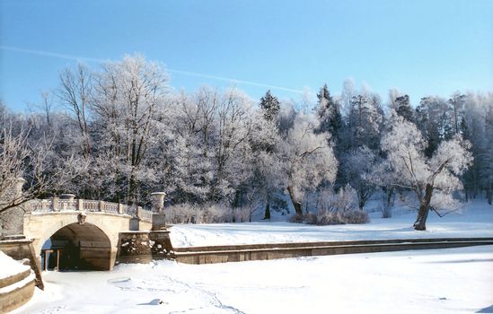 Winter river with old classical bridge in the park