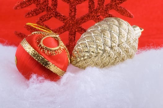 Red Christmas bauble with golden pine cone and red snowflake in the background