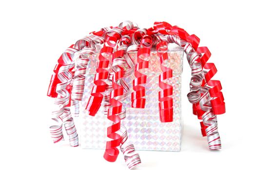 Gift wrapped in metallic paper with red, white and silver ribbon isolated on white.
