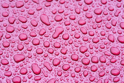 a picture of water drops on a red metal surface