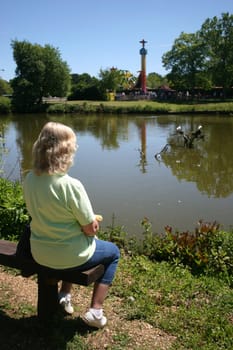 Carole sitting on a bench looking over the look at a theme park in the UK.