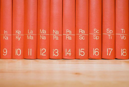 Close view on red books standing in a wooden bookshelf.