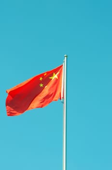 Chinese national five-star red flag fluttering in the wind against blue sky