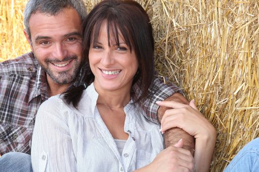 Farming couple sitting in the hay