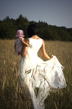 Women with her baby is walking  threw the field of  rye.