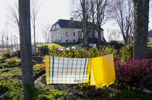 Exterior of old house with slate roof. Laundry drying outside on a rope in the yard.