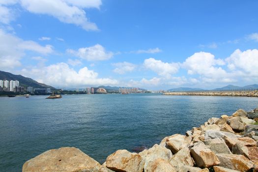 Coastal landscape in Hong Kong at daytime, with many residential buildings. 