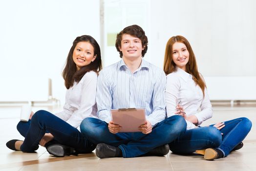 portrait of a group of young people sitting on the floor, man and two attractive women