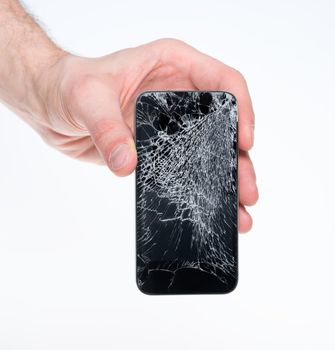 Studio closeup of a male hand, holding a smartphone with a cracked screen, isolated on a white background