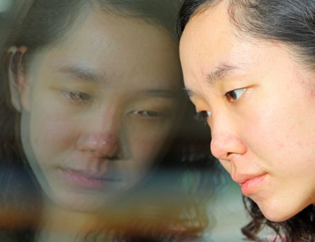 Asian girl with sad face, looking at the glass on train