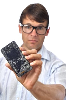 Young Caucasian man holds up smart phone with shattered screen on white background