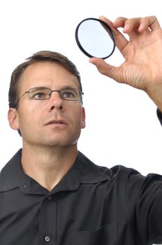 Photographer holds up circular polarizer filter to check for dirt on white background