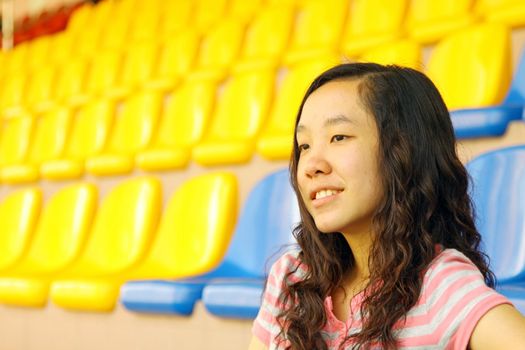 Asian girl on stadium, she is watching matches on court. 