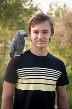 Portrait of a teenage boy with a gray parrot Jaco.